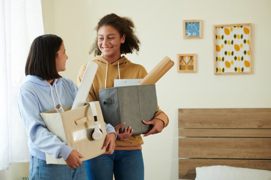 Two people carrying moving boxes into a new apartment
