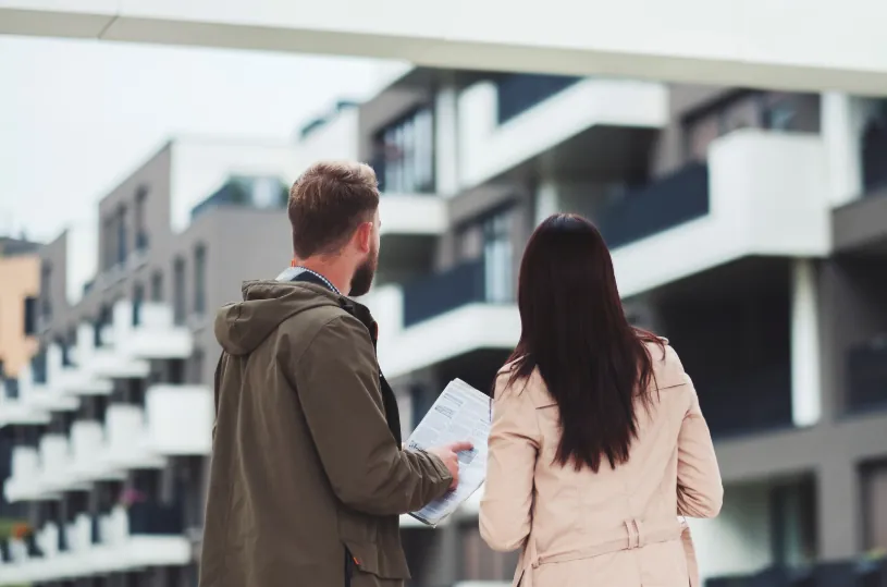 A couple reviewing documents while touring a modern apartment complex, highlighting key factors in deciding when to start looking for apartments.