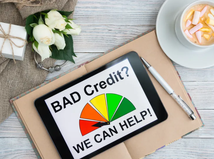 A tablet displaying "Bad Credit? We Can Help!" on a desk, symbolizing financial assistance and expert guidance on how to get an apartment with bad credit.