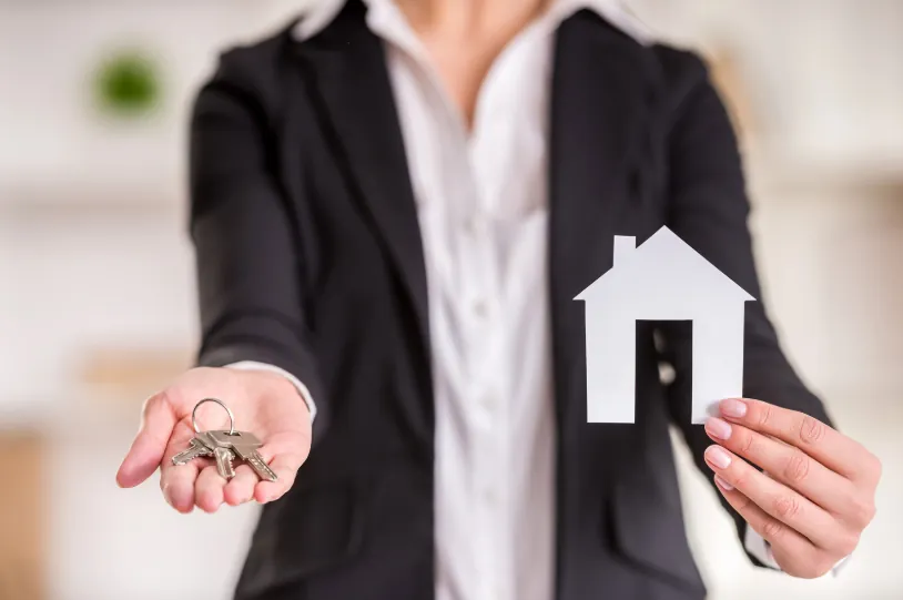 A real estate agent holding house keys and a paper home cutout, representing possible rental approval options for how to get an apartment with bad rental history.