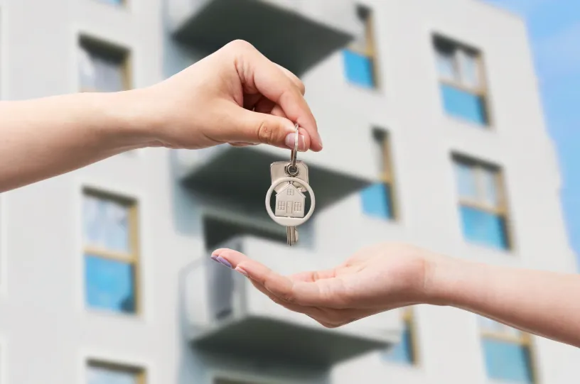 A close-up of a hand giving apartment keys to another person, symbolizing lease agreements and the right timing for when to start looking for apartments.