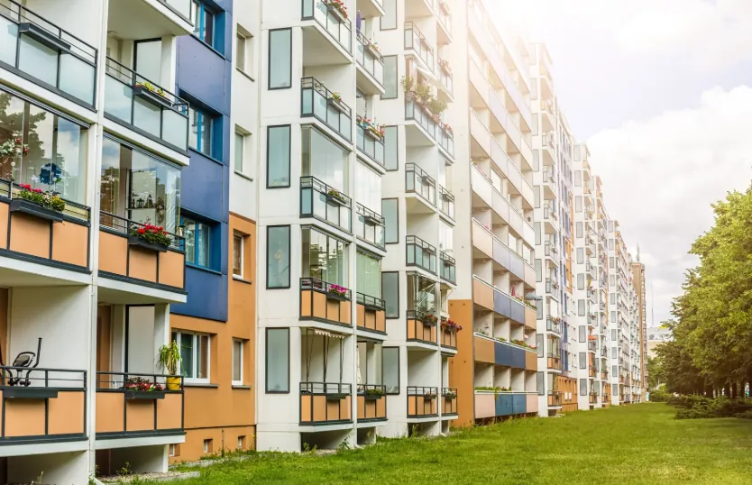 A row of colorful apartment buildings with balconies and green space, illustrating available rental options and when to start looking for apartments.