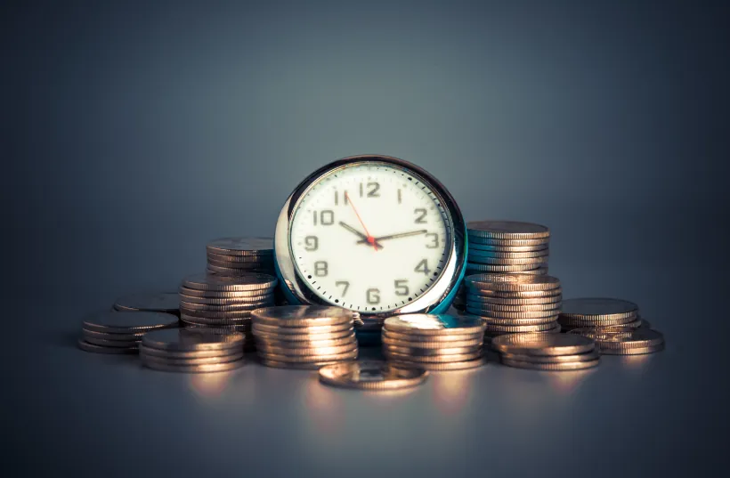 A clock surrounded by stacked coins, symbolizing the time and financial savings associated with using "what is an apartment locator" services.